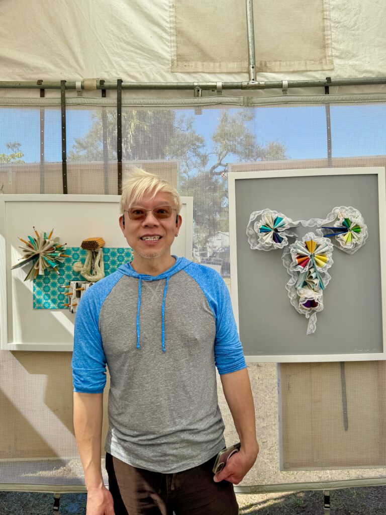 Daniel Lai emerging artist award winner at Gulfport Fine Arts Festival 2026 standing with mixed media artwork at Clymer Park Gulfport Florida