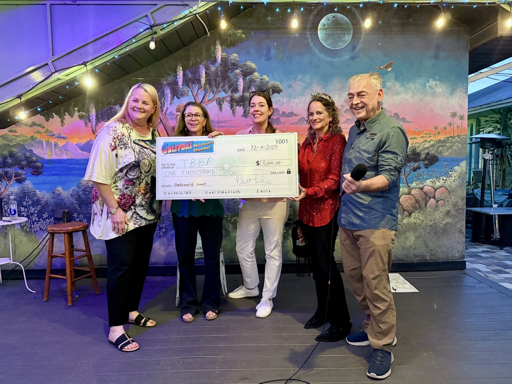 Gulfport Merchants Chamber board members present a Gecko World Grant check to the Tampa Bay Butterfly Foundation during a community event in Gulfport, Florida